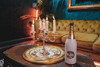 a bottle of champagne sits on a table next to candles