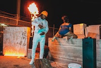 a man and a woman standing next to a fire
